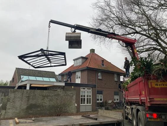 Vrachtwagen met kraan tilt materiaal over een woning